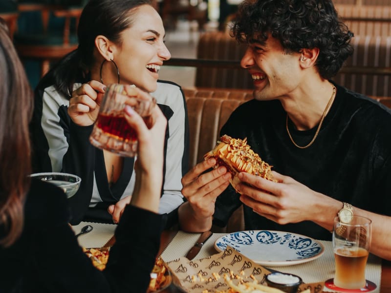 A couple laughing and enjoying their meal at a restaurant table